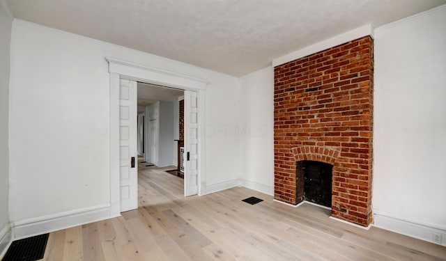 unfurnished living room with ornamental molding, a fireplace, and light hardwood / wood-style flooring