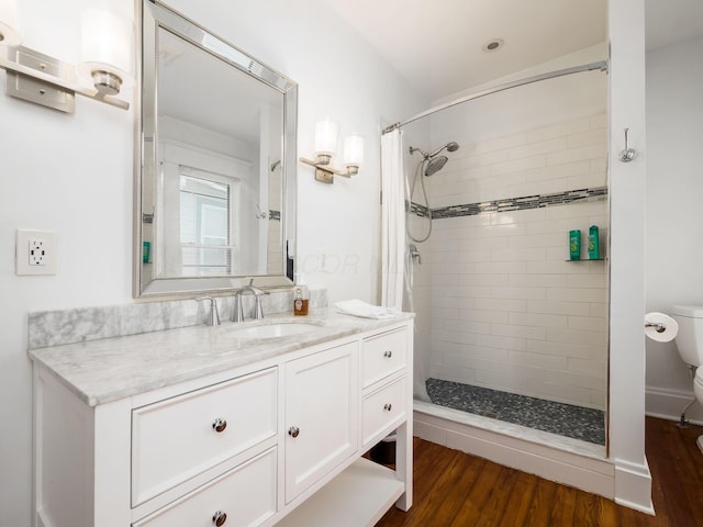 bathroom with wood-type flooring, vanity, toilet, and curtained shower