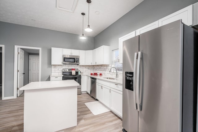 kitchen featuring appliances with stainless steel finishes, decorative light fixtures, sink, and white cabinets