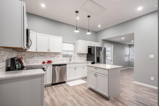 kitchen with stainless steel appliances, decorative light fixtures, a center island, and white cabinets