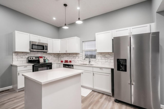 kitchen with a kitchen island, appliances with stainless steel finishes, pendant lighting, sink, and white cabinets