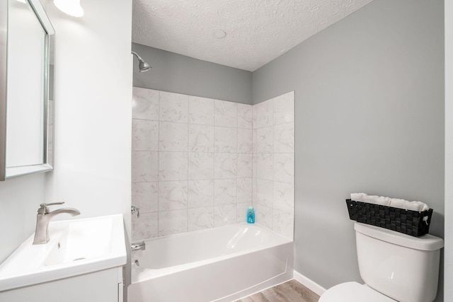 full bathroom featuring tiled shower / bath, wood-type flooring, vanity, toilet, and a textured ceiling