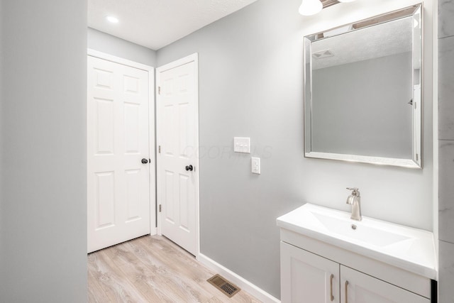 bathroom featuring hardwood / wood-style flooring, vanity, and a textured ceiling