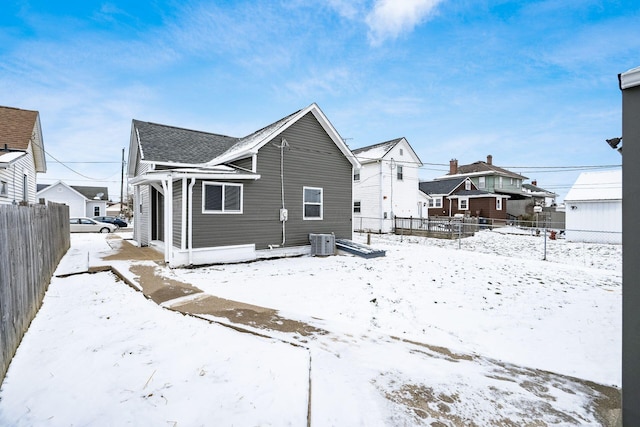 snow covered rear of property with central AC unit