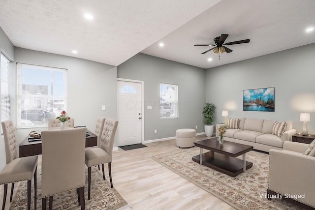 living room with ceiling fan, light hardwood / wood-style floors, and a textured ceiling