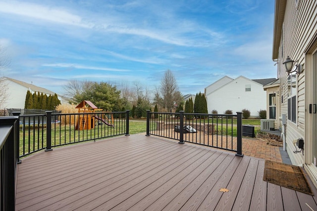 deck with a lawn, cooling unit, and a playground