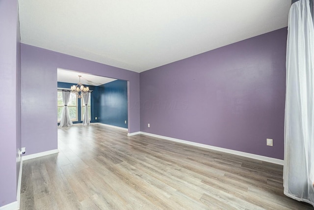 empty room featuring light hardwood / wood-style floors and a notable chandelier