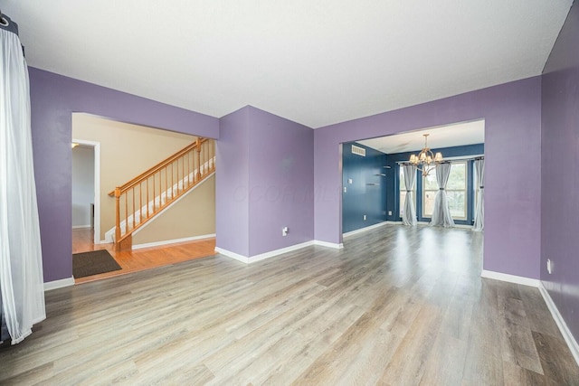 unfurnished living room with an inviting chandelier and light hardwood / wood-style flooring