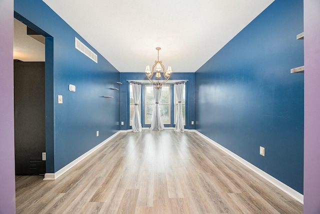 empty room featuring hardwood / wood-style floors and a notable chandelier