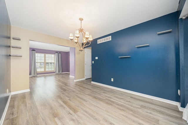 unfurnished room with light hardwood / wood-style flooring and an inviting chandelier