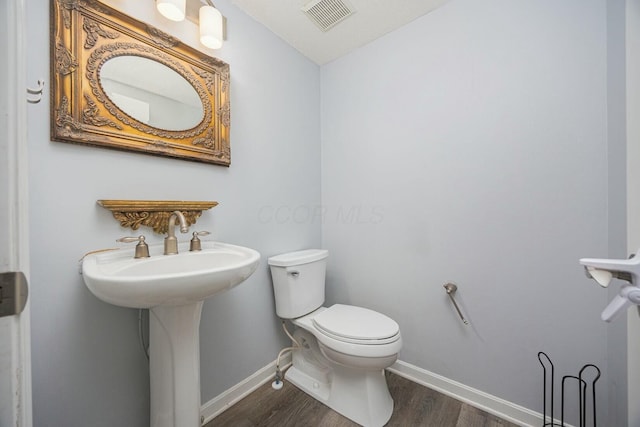 bathroom with toilet and wood-type flooring