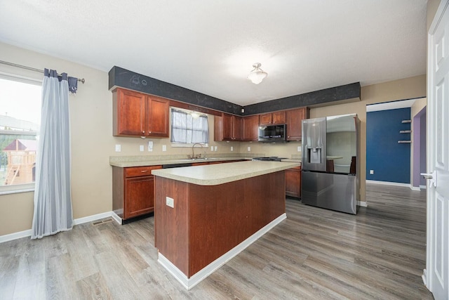 kitchen with stainless steel fridge, plenty of natural light, a kitchen island, and light hardwood / wood-style floors