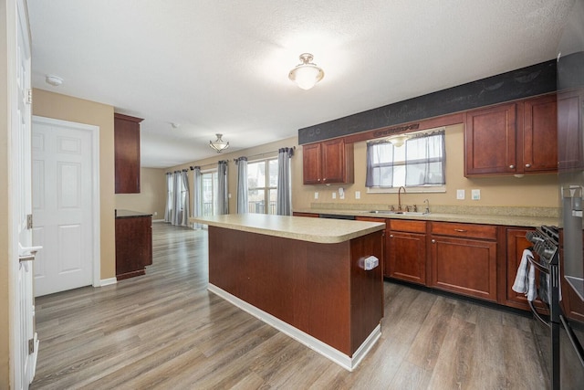 kitchen with a textured ceiling, a kitchen island, wood-type flooring, and sink