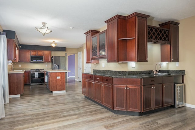 kitchen with light hardwood / wood-style flooring, stainless steel appliances, a kitchen island, and sink