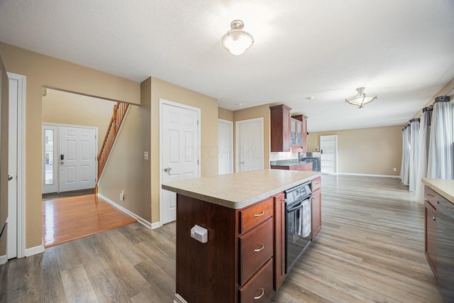 kitchen with black oven, a kitchen island, light hardwood / wood-style floors, and a textured ceiling