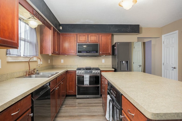 kitchen with appliances with stainless steel finishes, light hardwood / wood-style flooring, and sink