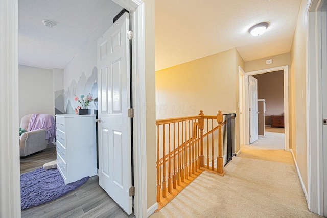 hallway with light hardwood / wood-style flooring and a textured ceiling