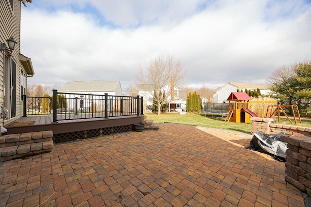 view of patio featuring a playground, a wooden deck, and a trampoline