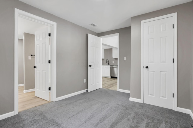 unfurnished bedroom with light carpet and sink