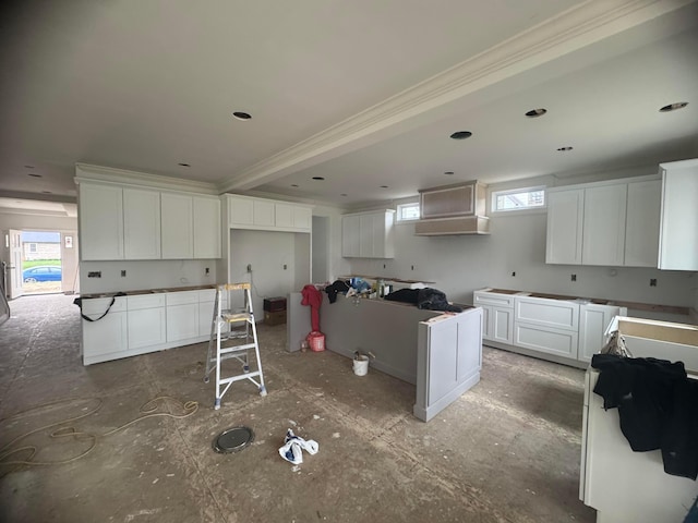 kitchen with a wealth of natural light, white cabinetry, and crown molding