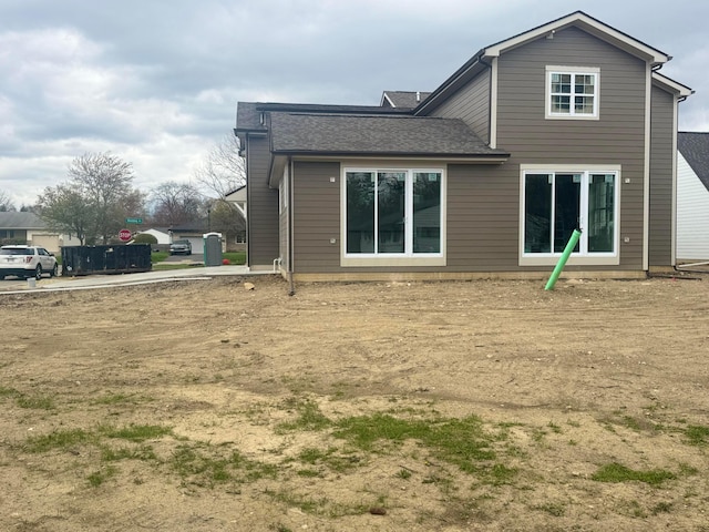 rear view of property with roof with shingles