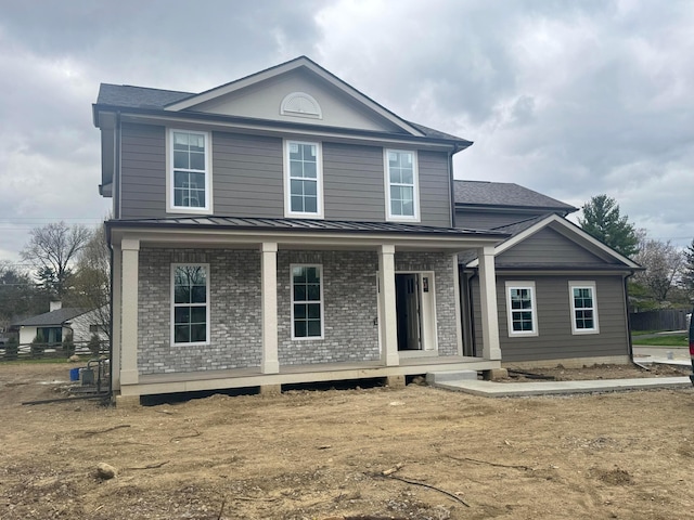 traditional home with brick siding, a standing seam roof, metal roof, and covered porch