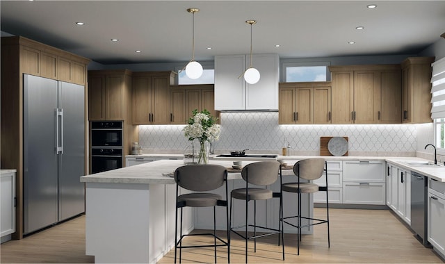 kitchen with stainless steel appliances, a sink, a kitchen island, and backsplash