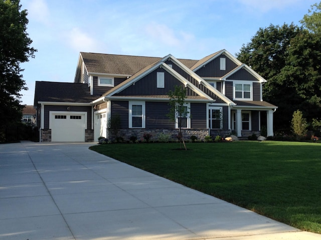 craftsman-style home with an attached garage, stone siding, driveway, and a front lawn