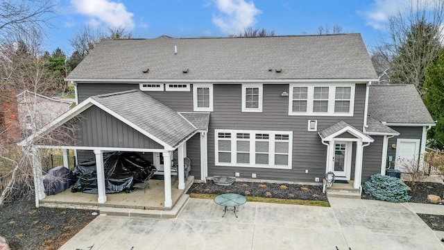 rear view of property featuring a carport, roof with shingles, a patio area, and driveway