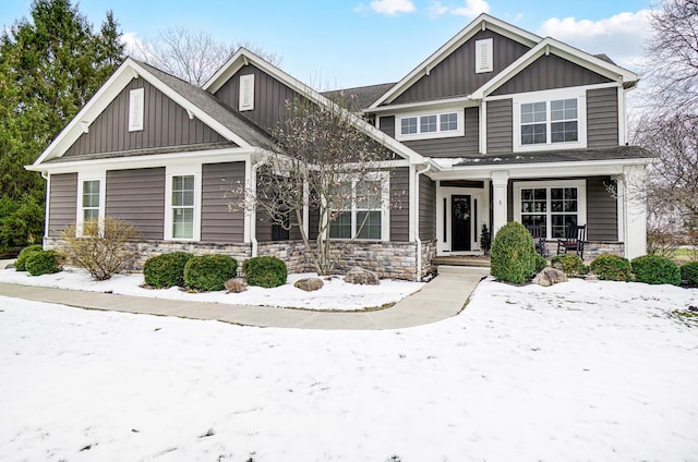 craftsman house featuring stone siding, a porch, board and batten siding, and a shingled roof