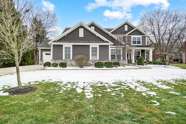 craftsman-style house featuring an attached garage, stone siding, board and batten siding, and a front yard