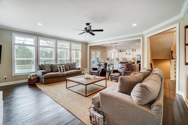 living room featuring baseboards, dark wood finished floors, crown molding, and ceiling fan with notable chandelier