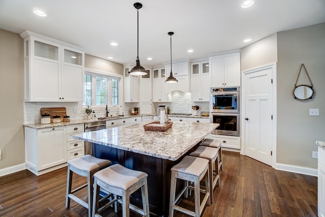 kitchen featuring dark wood-style floors, appliances with stainless steel finishes, a breakfast bar, and a center island