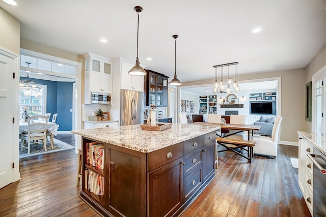 kitchen with dark brown cabinetry, glass insert cabinets, appliances with stainless steel finishes, dark wood-style flooring, and white cabinetry