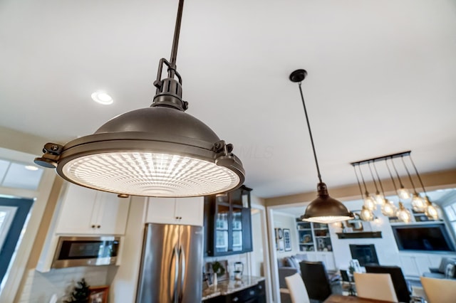 details with appliances with stainless steel finishes, decorative light fixtures, and white cabinets