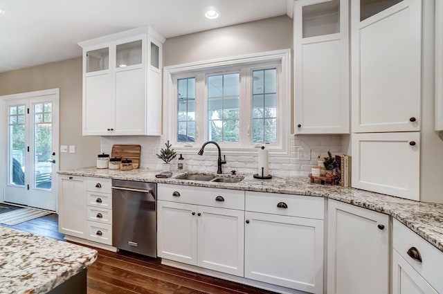 kitchen with white cabinets, dark wood-style floors, backsplash, stainless steel dishwasher, and a sink