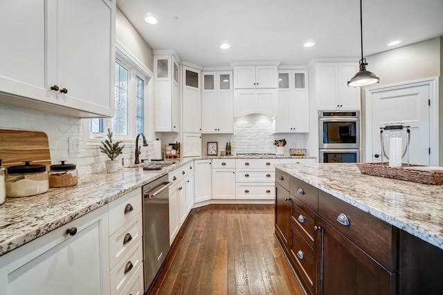 kitchen featuring appliances with stainless steel finishes, glass insert cabinets, white cabinets, a sink, and dark brown cabinets