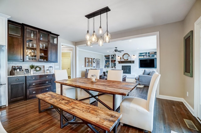 dining room with dark wood-style floors, ceiling fan, a glass covered fireplace, and baseboards