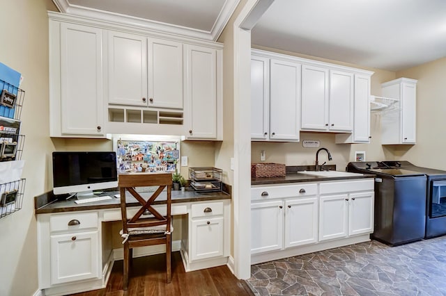 kitchen featuring dark countertops, a sink, built in study area, and white cabinets