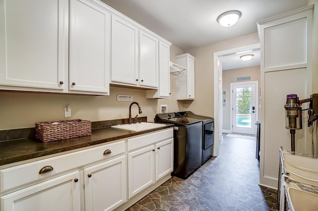 kitchen with dishwashing machine, washing machine and dryer, a sink, white cabinetry, and dark countertops