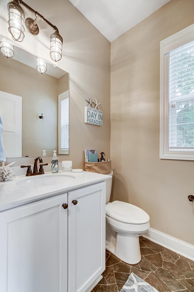 bathroom featuring baseboards, vanity, and toilet