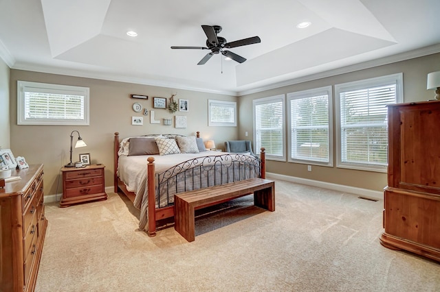 bedroom with a raised ceiling, light colored carpet, crown molding, and baseboards