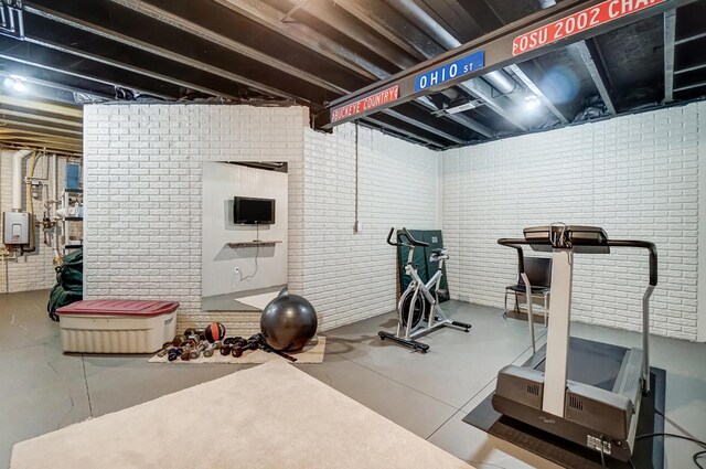 workout area featuring tankless water heater and brick wall