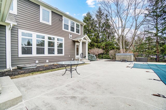 view of patio featuring a hot tub, fence, and a fenced in pool