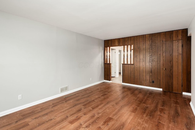 unfurnished room featuring dark hardwood / wood-style flooring and wooden walls