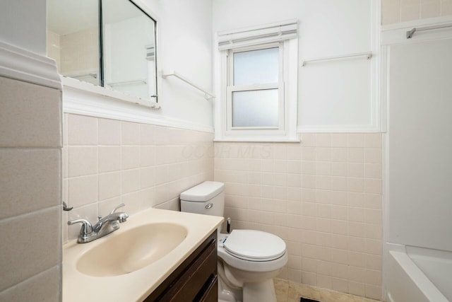 bathroom featuring vanity, tile walls, and toilet