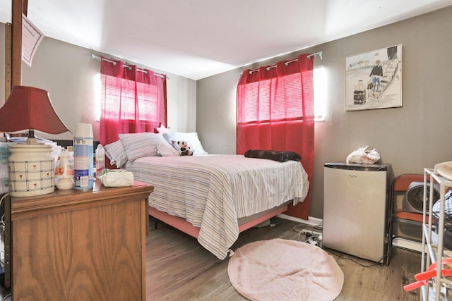 bedroom with stainless steel fridge and dark hardwood / wood-style floors