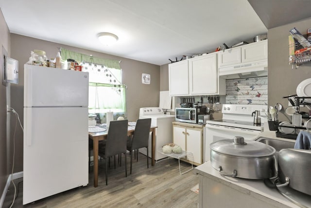 kitchen with washer / dryer, white cabinetry, white appliances, light wood-type flooring, and sink