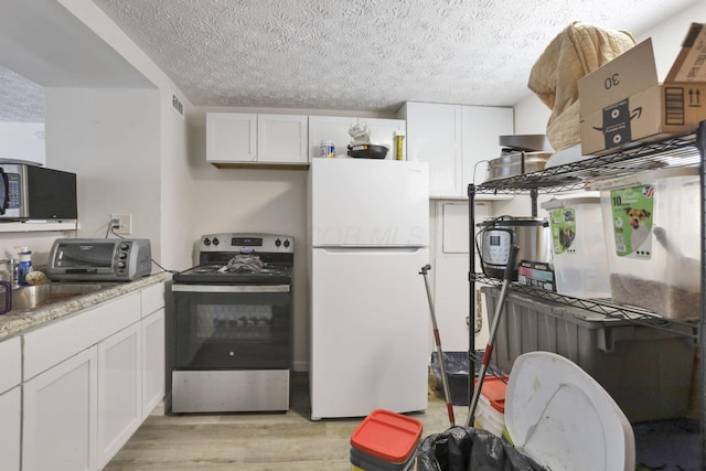 kitchen featuring a textured ceiling, appliances with stainless steel finishes, white cabinetry, sink, and light wood-type flooring