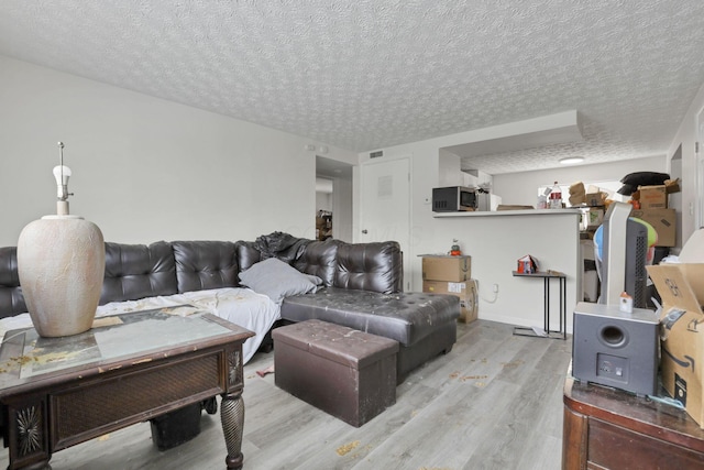 living room featuring a textured ceiling and light hardwood / wood-style flooring